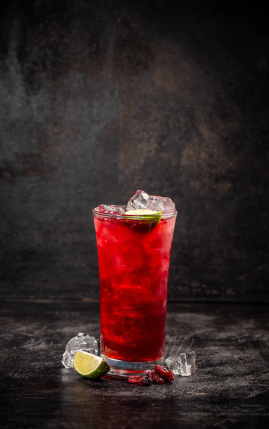 Refreshment alcoholic red cranberry and lime cocktail with ice on dark background, copy space - 写真・画像