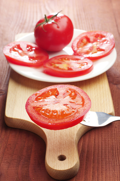 Slices tomato on a fork and in a plate - 写真・画像