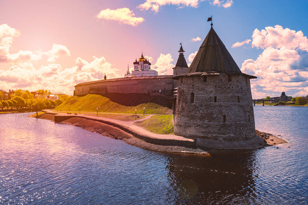 Pskov kremlin tower with blue cloudy sky in background. River in foreground. - Foto, Bild