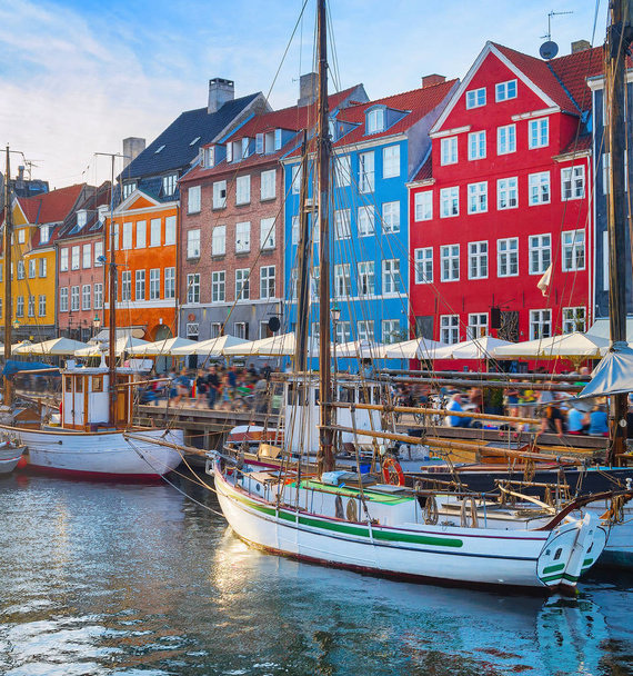 Tourists walking at Nyhavn embankment with moored tour boats at sunset, Copenhagen, Denmark - Photo, image