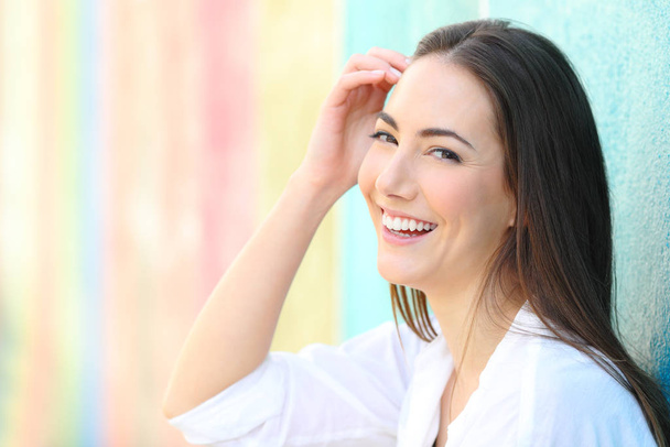Gelukkige vrouw met perfecte glimlach poseren kijken camera in een kleurrijke achtergrond - Foto, afbeelding