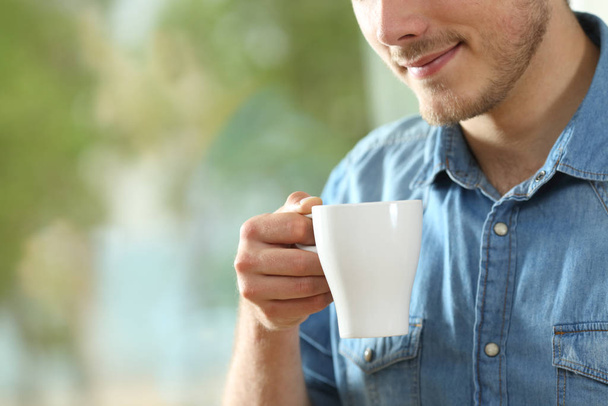 Close up portrait of a relaxed man holding a hot drink cup at home - Foto, immagini