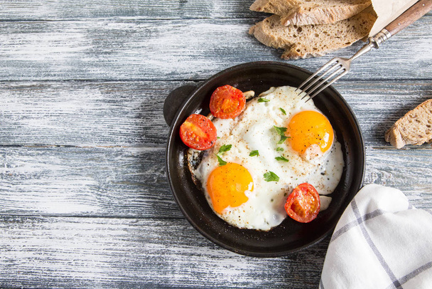 Fried egg. Close up view of the fried egg on a frying pan with cherry tomatoes and parsley. - Fotoğraf, Görsel
