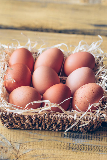 Basket of raw chicken eggs on the wooden background - Фото, зображення