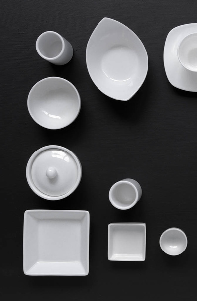 białe, nowoczesne zastawy stołowe w różnych wzorach na czarnym tle, fotografowanie w studio ze światłem dziennym - Zdjęcie, obraz