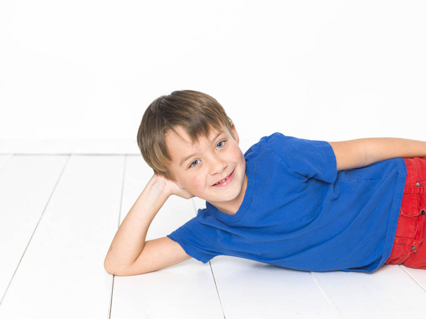 cool, six year old boy with red trousers and blue shirt on white floor - Foto, Bild