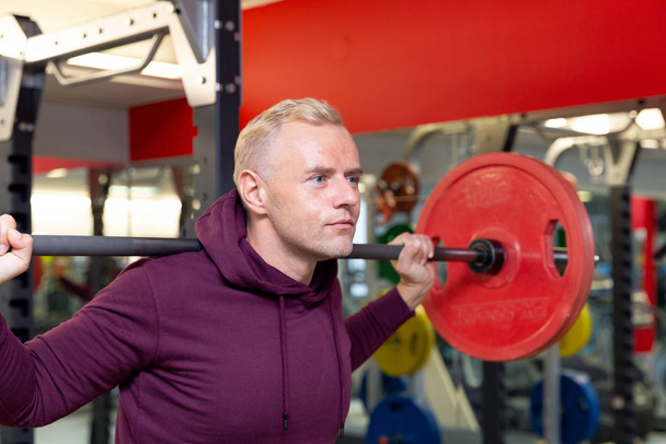 Young man lifting heavy weights during a workout session. Man training with barbell - Foto, afbeelding