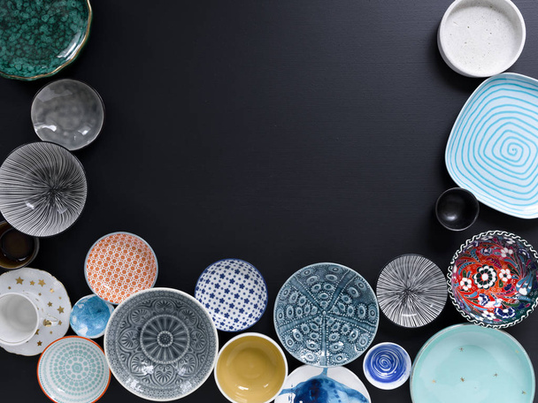 white and coloured tableware in different designs on a black background, photographed from above - Foto, immagini