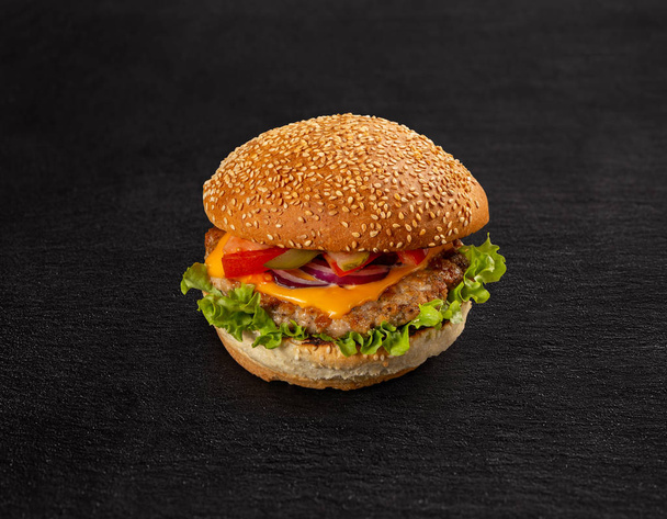 Delicious grilled burger on black slate background - Фото, зображення