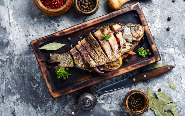 Grilled whole fish with citrus,vegetable and spices on rustic kitchen board.Cooked baked grilled fish - Foto, afbeelding