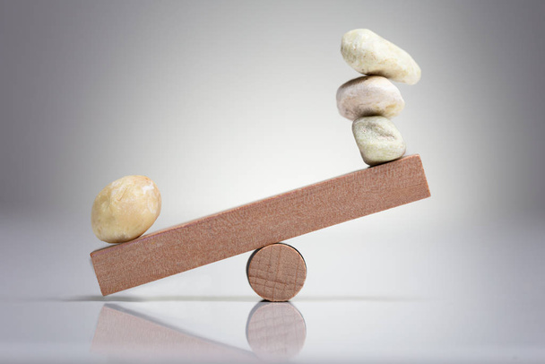 Pebble Stones Balancing On Wooden Seesaw Over The White Background - Fotó, kép