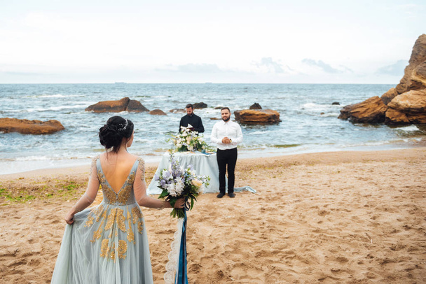 wedding couple on the ocean with a priest - Fotoğraf, Görsel