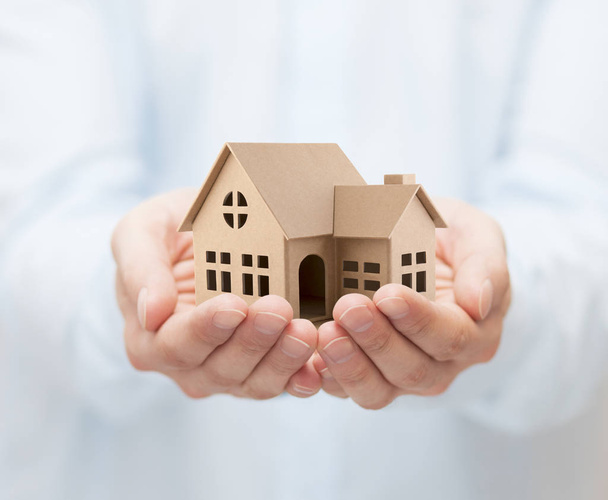 Property insurance. Cardboard house miniature in hands - Foto, immagini