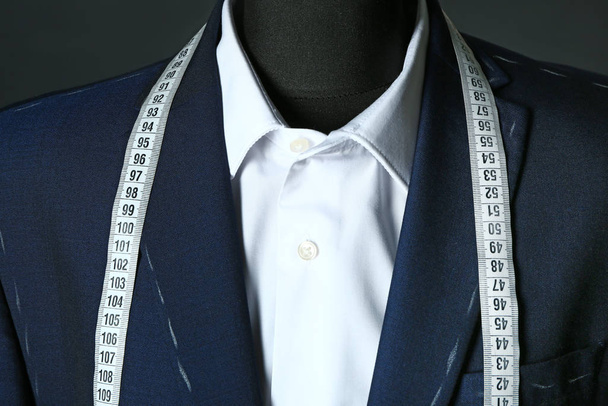Tailor's mannequin with unfinished clothes and measuring tape on dark background, closeup - Photo, Image