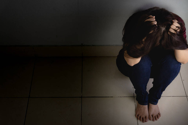 sad woman hug her knee and cry sitting alone in a dark room. Dep - 写真・画像