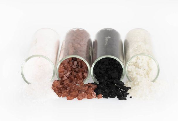 Alaea salt, hawaiian black salt, grey salt and fleur de sel pouring from jars and isolated now white. - Фото, изображение