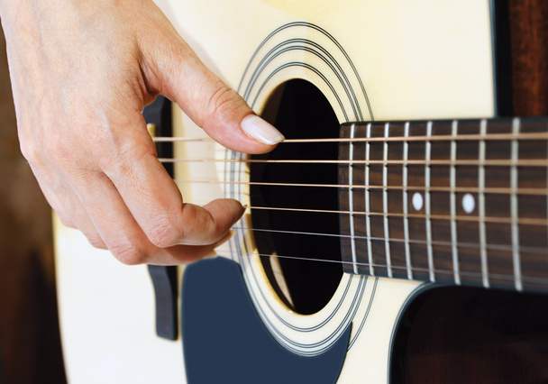 woman hand plucking strings on a guitar - Foto, afbeelding