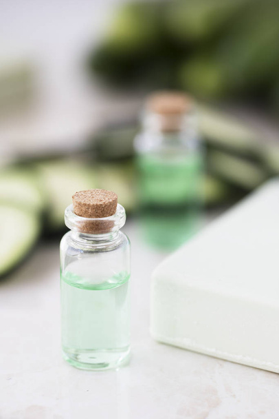 Cucumber extract in small bottle with bar of soap and cucumber slices. - Foto, Imagem