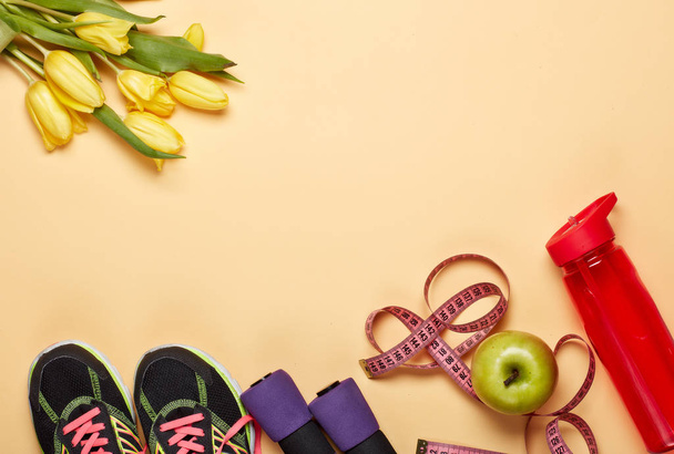 Female fitness still life. Sport accessories, tulips flowers on yellow background. Mockup. Planning of diet and trainings. Top view with copy space. Healthy lifestyle concept. Slimming - 写真・画像