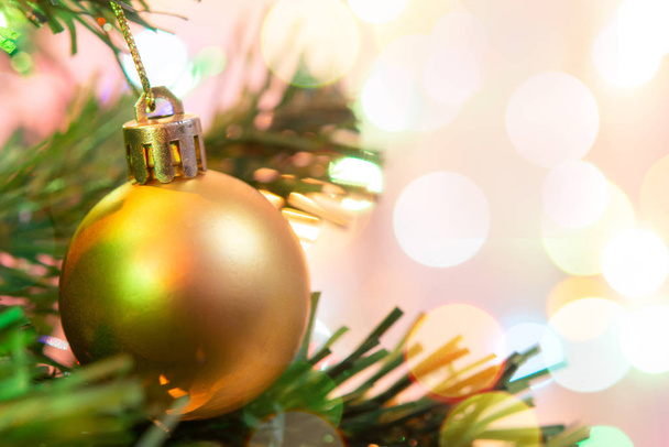 Χριστουγεννιάτικη διακόσμηση. Κρεμαστά χρυσά μπαλάκια σε κλαδιά πεύκου - Φωτογραφία, εικόνα