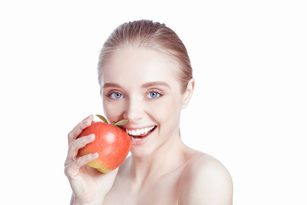 Portrait of happy smiling young beautiful woman eating red apple, over white background - Фото, изображение
