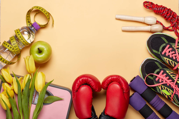 Female fitness still life. Sport accessories, tulips flowers and scales on a yellow background. Mockup. Planning of diet and trainings. Top view with copy space. Healthy lifestyle concept. Slimming - 写真・画像