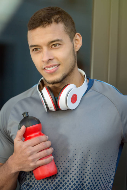 Young latin man water bottle smiling runner portrait format running sports training fitness outdoor - Fotó, kép