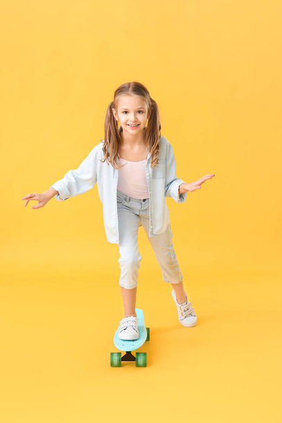 Cute little girl with skateboard on color background - Photo, Image