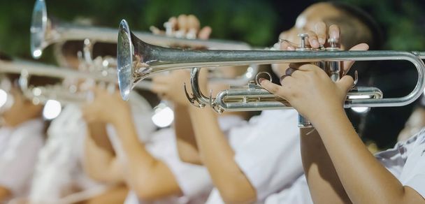 Male student with friends blow the trumpet with the band for performance on stage at night. - Photo, Image