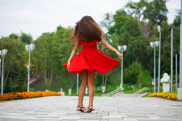Young beautiful woman in red dress walking on the summer street - Fotoğraf, Görsel