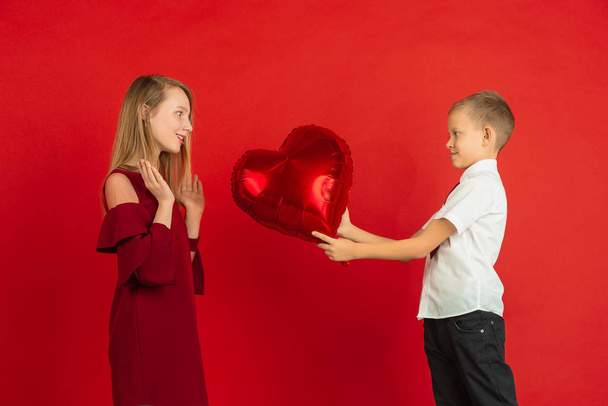 Valentines day celebration, happy caucasian kids isolated on red background - Фото, изображение