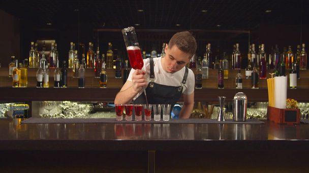 Barman nalévá alkohol do sklenic jeden po druhém - Fotografie, Obrázek