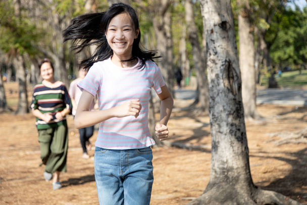 Saudável família asiática, menina criança feliz se divertir, desfrutar de jogo na natureza parque ao ar livre no verão, avó sênior, filha e neta jogar tag game, correndo alegre, ativismo de férias, relaxamento
 - Foto, Imagem