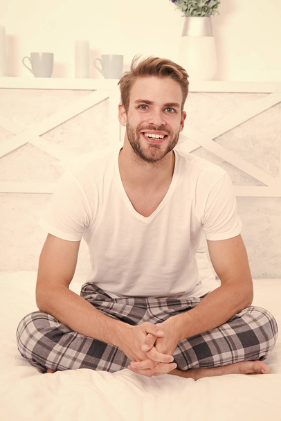 Good morning. Guy happy sit on bed. Man hipster in morning. Asleep and awake. Comfortable relax. Smiling guy wear pajamas at home. Cheerful positive energy. Handsome man enjoy his perfect morning - Foto, imagen