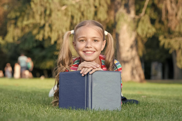 Školní čas. Rozvíjet starostlivě studující, kteří aktivně rostou a dosahují. Malé dítě čte knihu. Rozkošný knihomol. Školka, která čte příběhy, odpočívám zelený trávník. Roztomilý žák rád čte - Fotografie, Obrázek