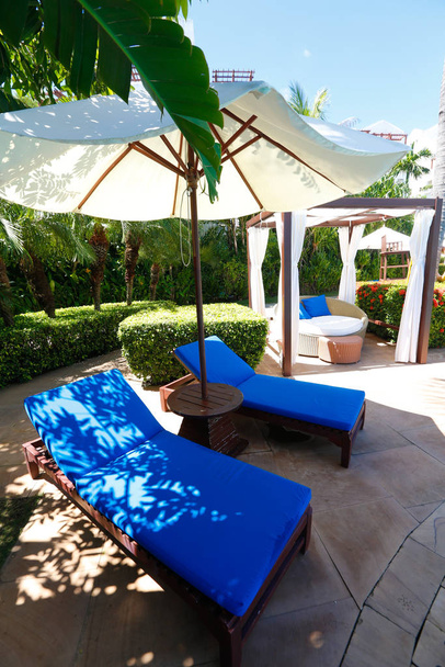 Pool, Liegestühle und Sonnenschirme in den Tropen am Mittag - Foto, Bild