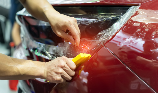 Worker install car paint protection film with spatula - Foto, imagen