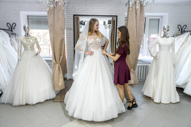 Krawiec mierzący suknię ślubną na pannie młodej w sklepie - Zdjęcie, obraz