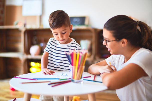 Bela professora e criança desenho menino desenhar usando lápis coloridos no jardim de infância
 - Foto, Imagem