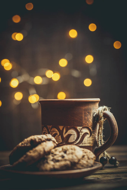 Brown clay vintage coffee mugs and delicious chocolate chip cookies on a wooden table in warm colors - Zdjęcie, obraz