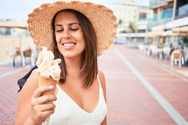 Молодая красивая женщина ест мороженое на пляже в солнечный день лета на каникулах
 - Фото, изображение