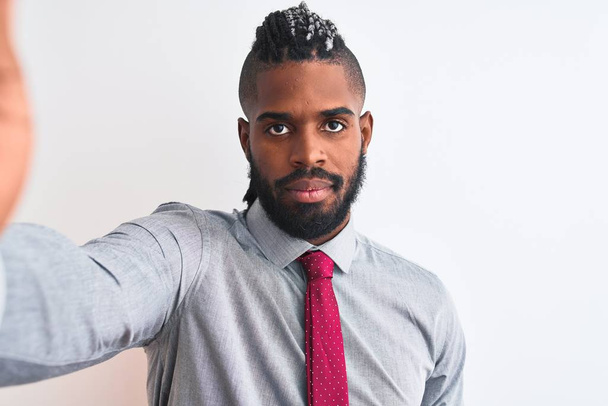 Homme d'affaires afro-américain faire selfie par caméra sur fond blanc isolé avec une expression confiante sur la pensée intelligente visage grave
 - Photo, image