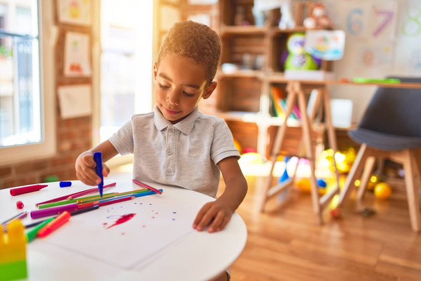 Όμορφη αφρικάνικη αμερικανική σχέδιο μικρών παιδιών χρησιμοποιώντας χαρτί και μαρκαδόρο στυλό στο νηπιαγωγείο - Φωτογραφία, εικόνα