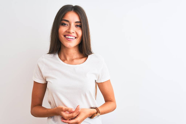 Young beautiful woman wearing casual t-shirt standing over isolated white background with hands together and crossed fingers smiling relaxed and cheerful. Success and optimistic - Photo, Image