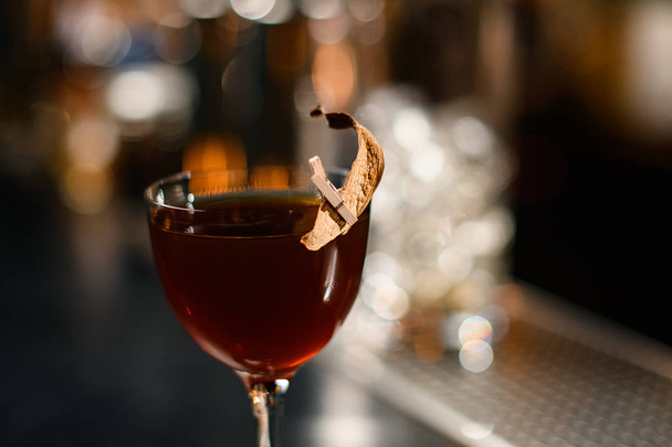 Delicious brown cocktail in the glass decorated with a dried leaf by a pin - Foto, immagini