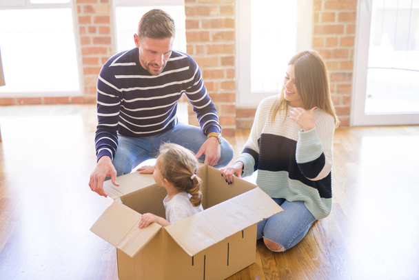 Linda famiily, criança brincando com seus pais montando caixa de fanny de papelão em nova casa
 - Foto, Imagem