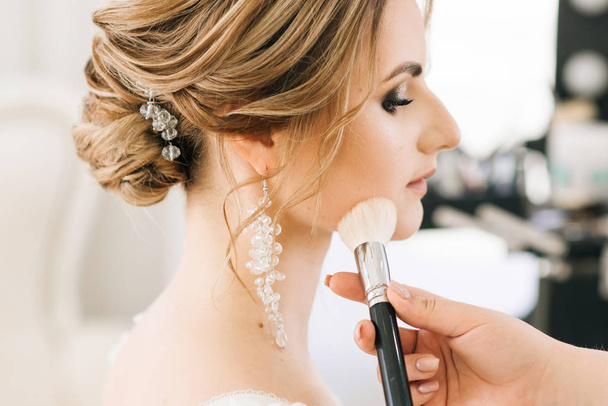 Portrait of a beautiful young bride in a bright room in a romantic atmosphere. Brides perform makeup - Фото, зображення