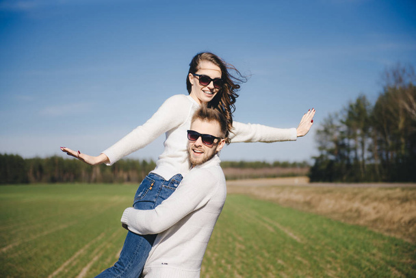 Happy girl and guy running and hugging on the field, love story travel concept, selective focus - Foto, imagen