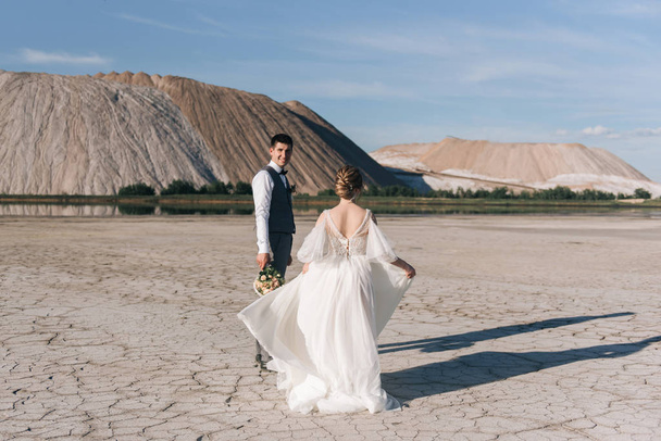 Beautiful elegant couple of newlyweds in love on a beautiful natural background of salt mountains and quarries - Photo, image