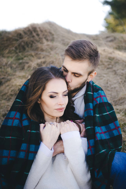 Happy girl and guy sitting in a field covered with a blanket, travel concept love story - Photo, Image